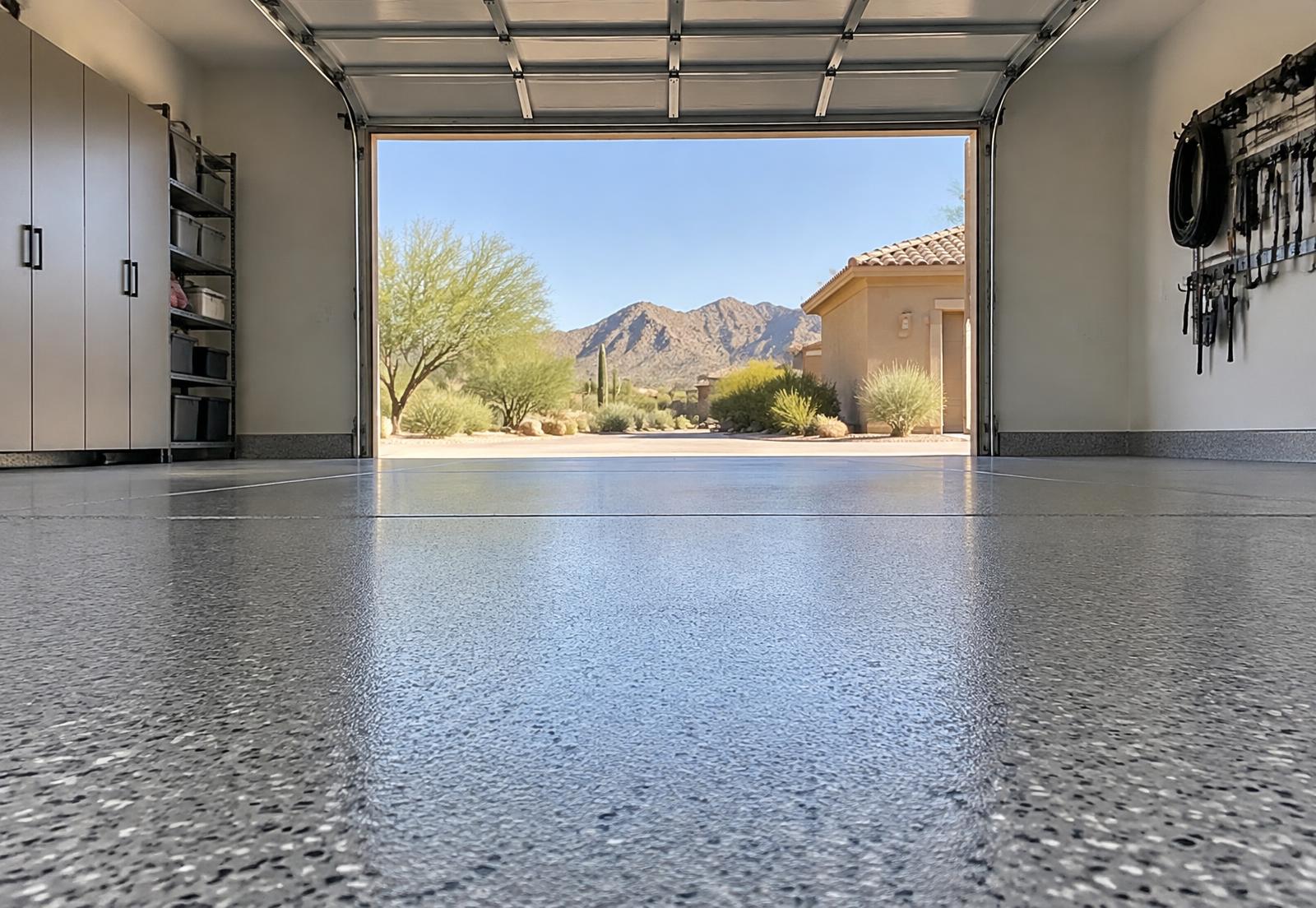 Floor-level view of a speckled garage coating looking out toward desert mountains